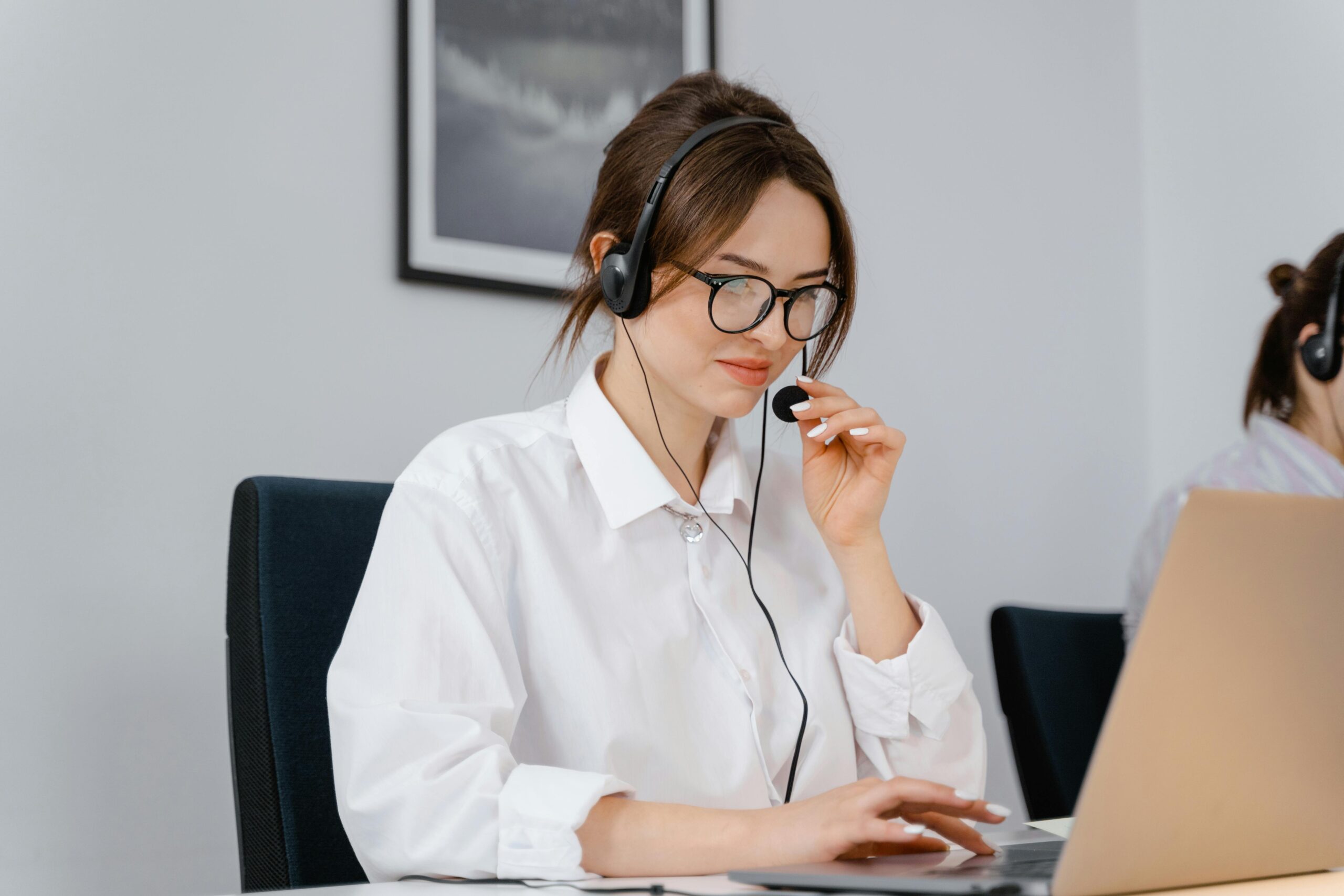 "Ung kvinde med headset arbejder koncentreret ved en bærbar computer – Made4Media ApS søger en ungarbejder til at opbygge presse- og medielister hjemmefra."